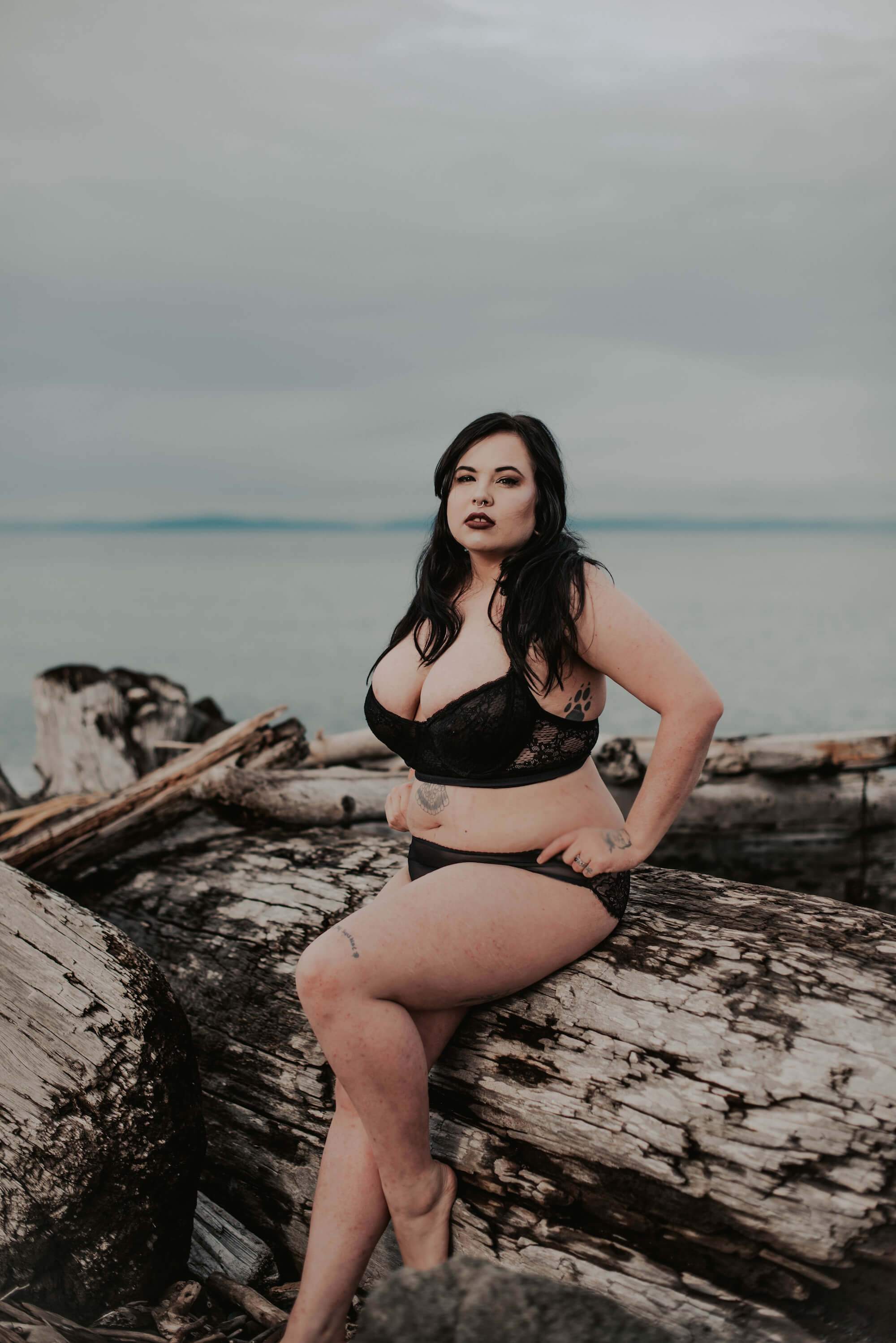 woman posing on driftwood on pacific northwest beach