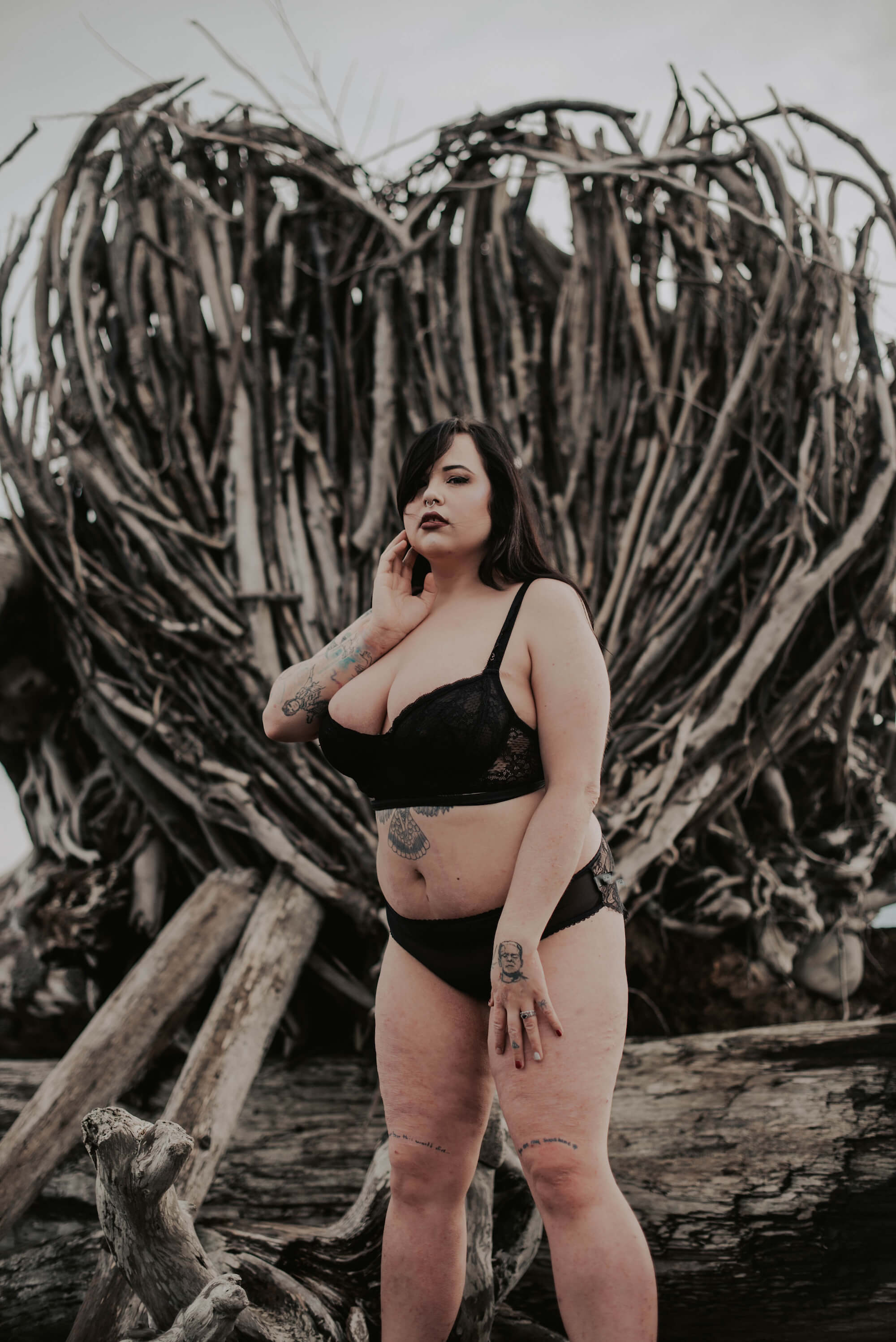 woman posing in black lingerie in front of heart shaped driftwood