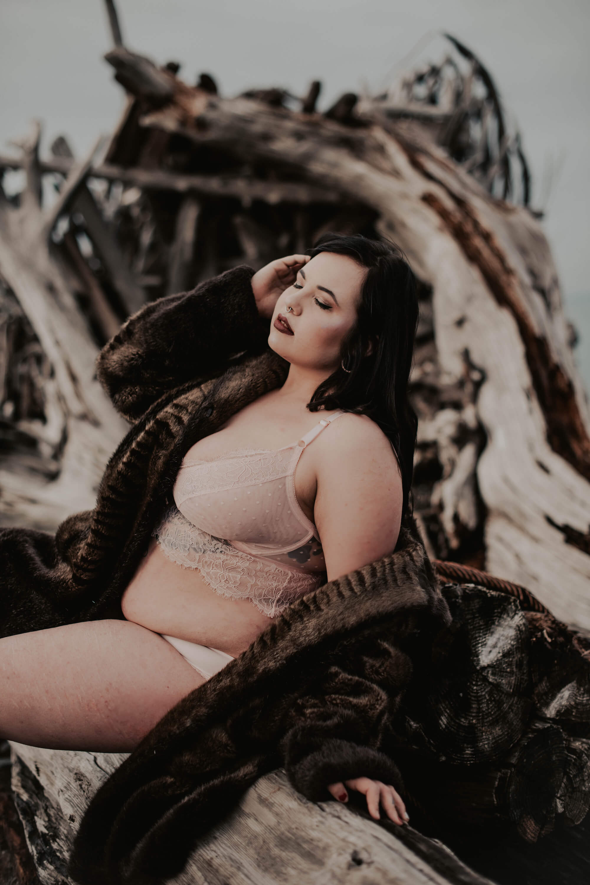 woman in pink lingerie set and brown fur coat on port angeles beach in the winter