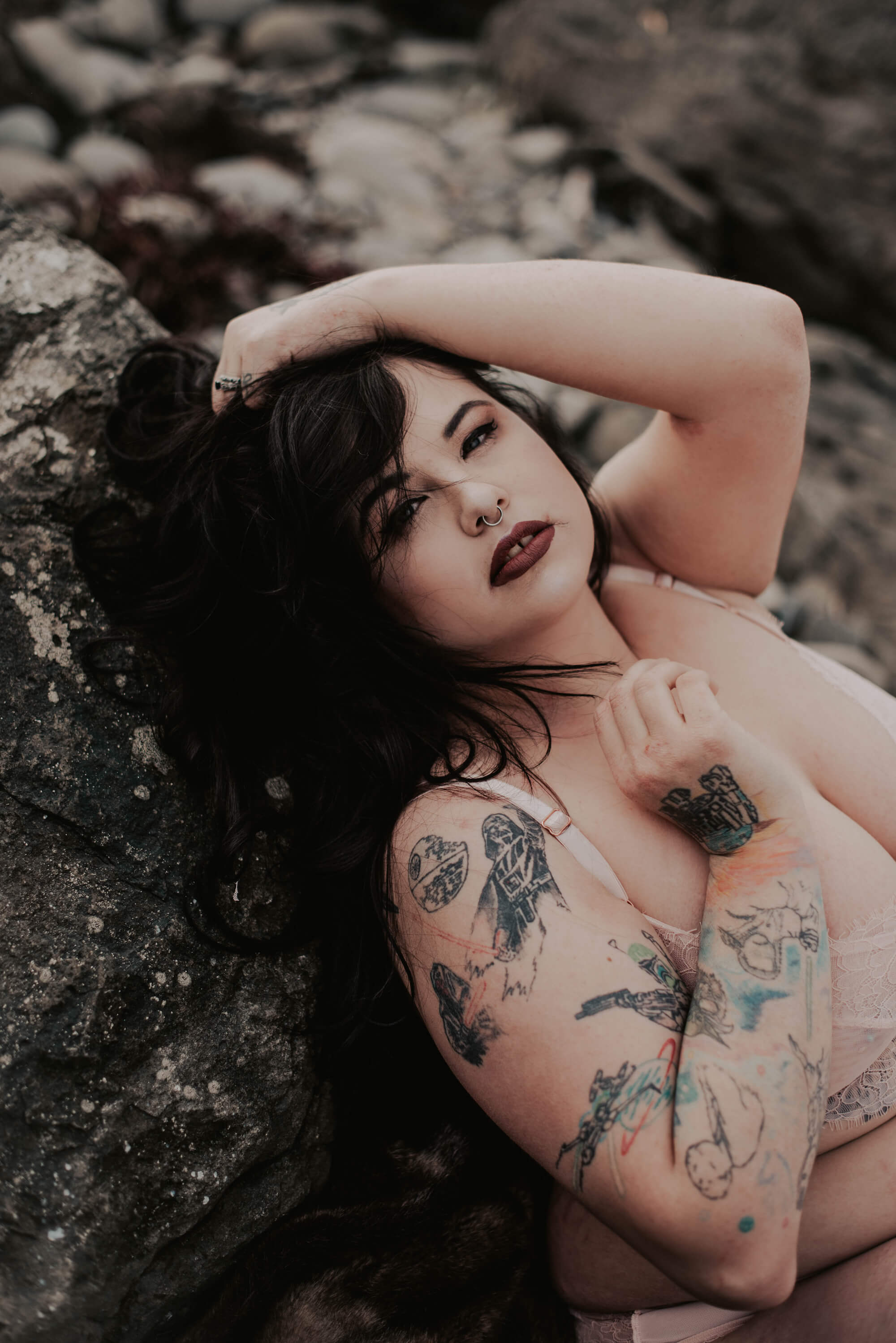 tattooed woman lying on rocks on port angeles beach