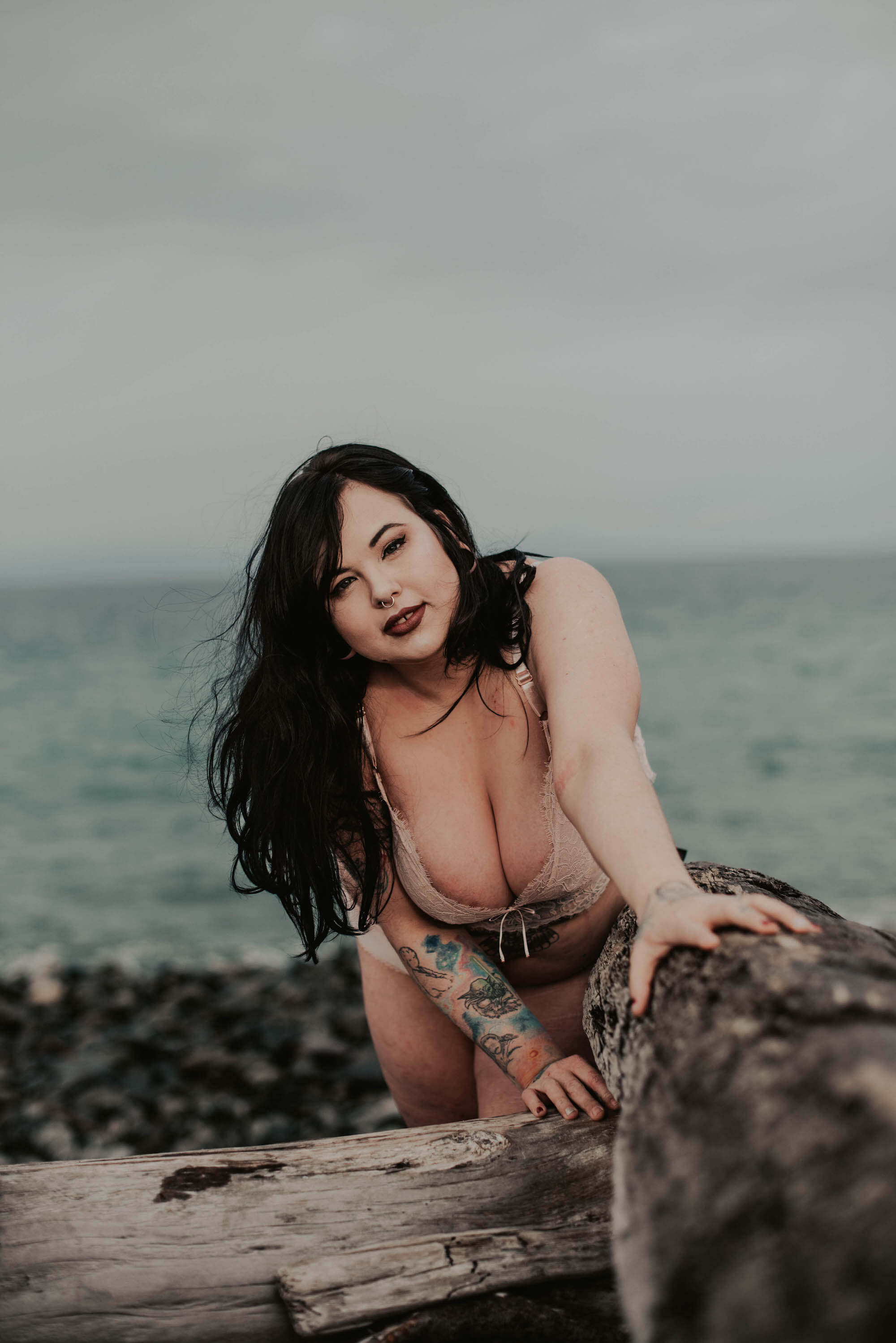 woman in pink lingerie posing on log on northwest beach