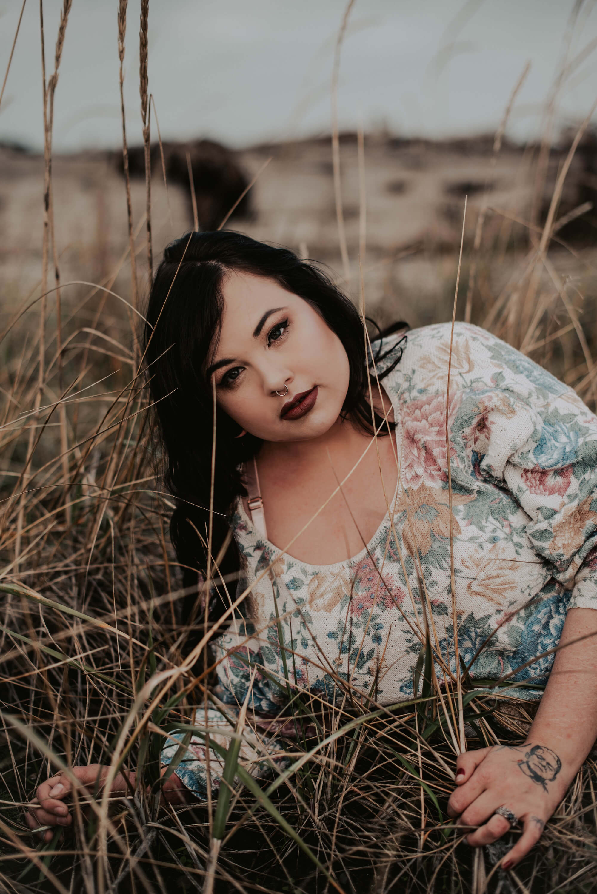 woman in floral sweatshirt lying in tall grass