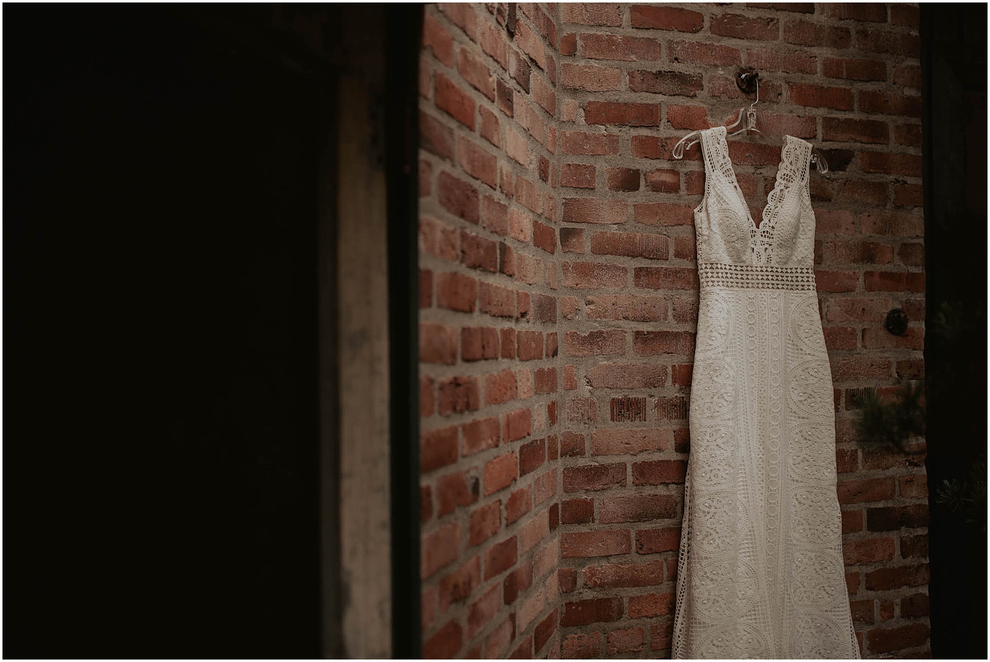 brides wedding dress hanging on brick wall