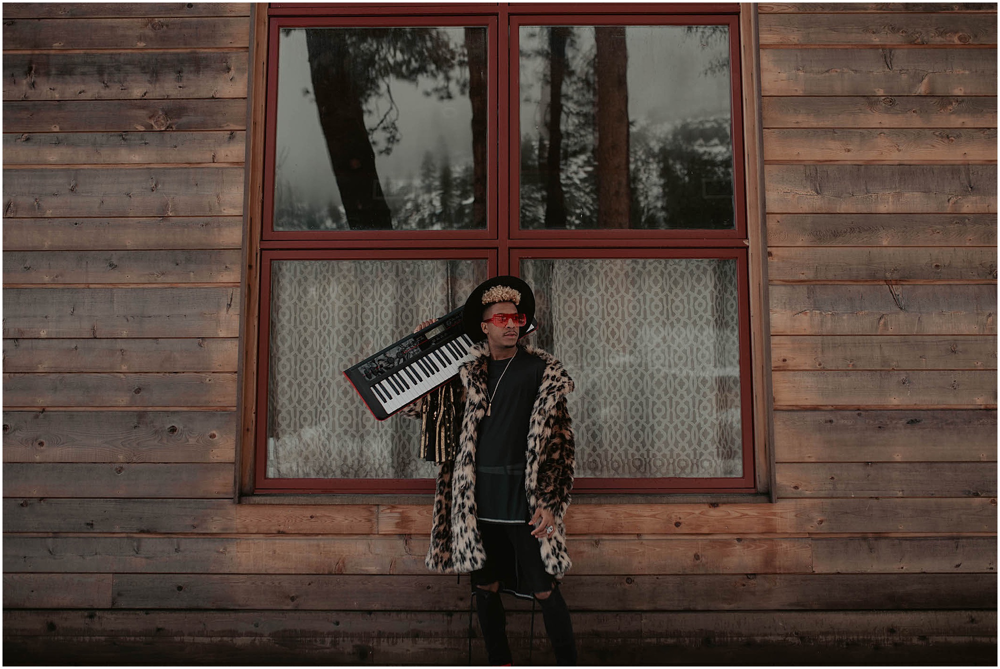 cabin in snowy woods, musician holding electric piano