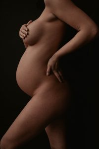naked pregnant woman on black background