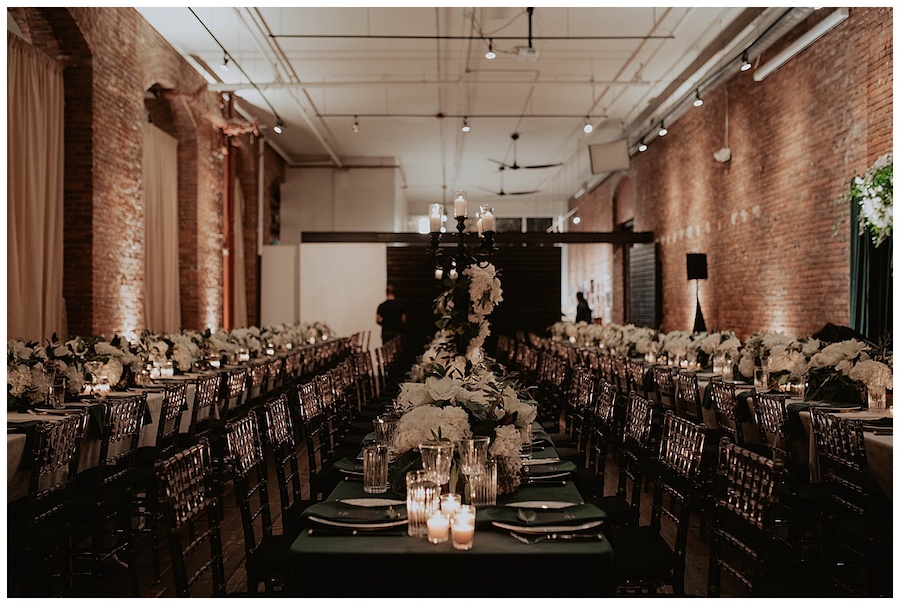 dark and moody wedding reception with all white flowers, candles and green napkins