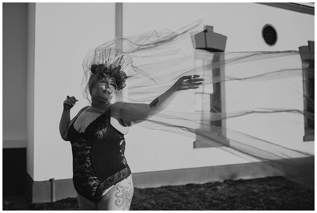 tattooed woman posing with fabric in front of lighthouse 
