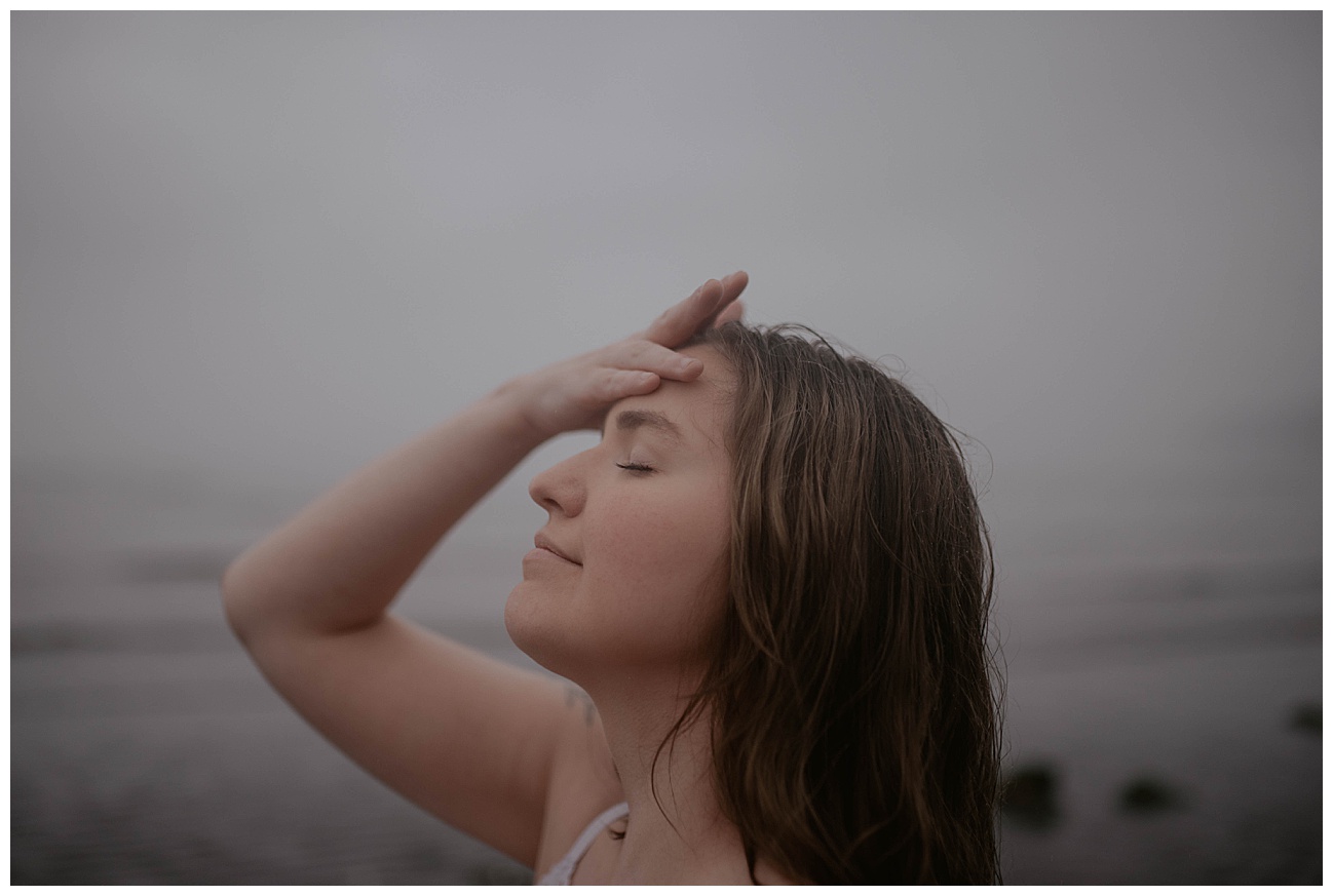 woman face tilting up in the rain on foggy beach