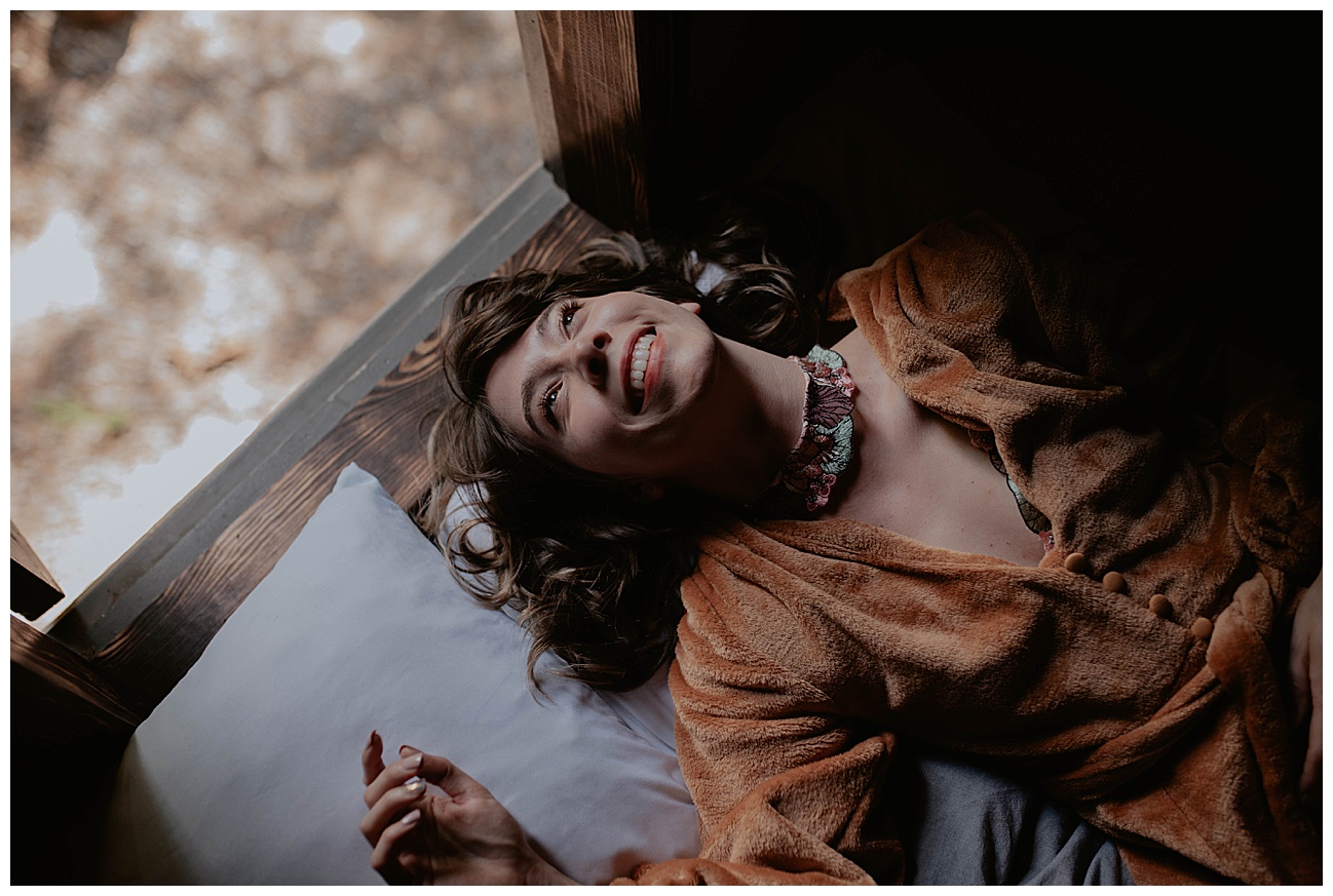 woman lying top in log cabin wearing a velvet orange robe