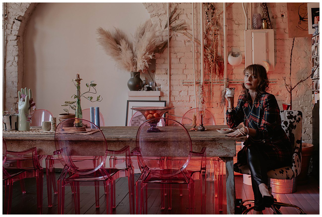 woman sitting at head of dining table with teach cup and hot pink chairs