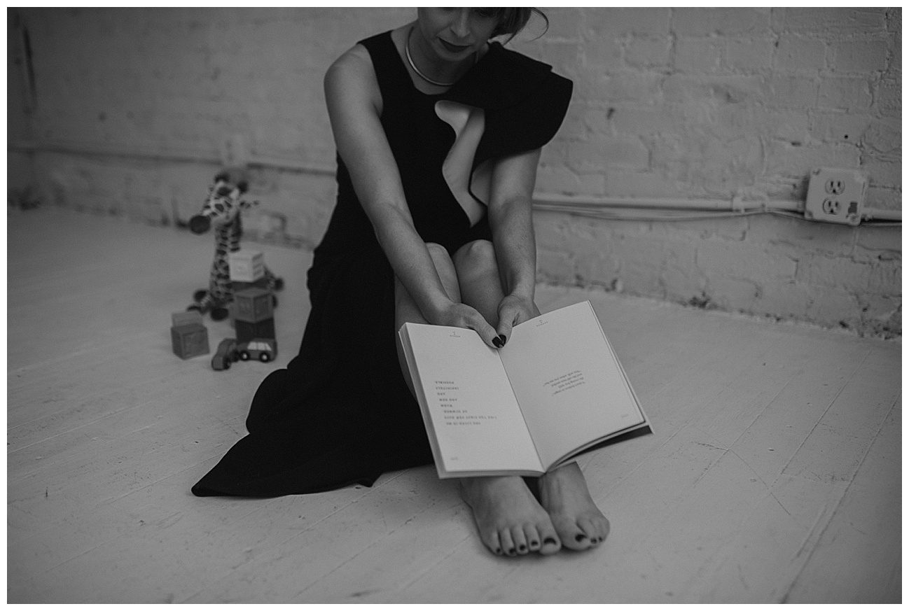 woman in black floor length dress sitting on the floor readying a book