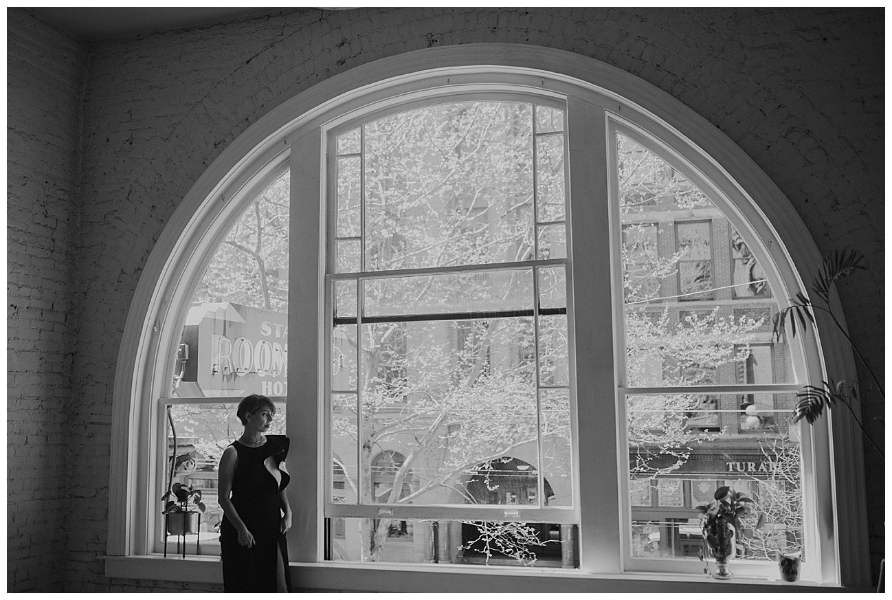 woman in fancy black dress standing by a large domed window in downtown seattle