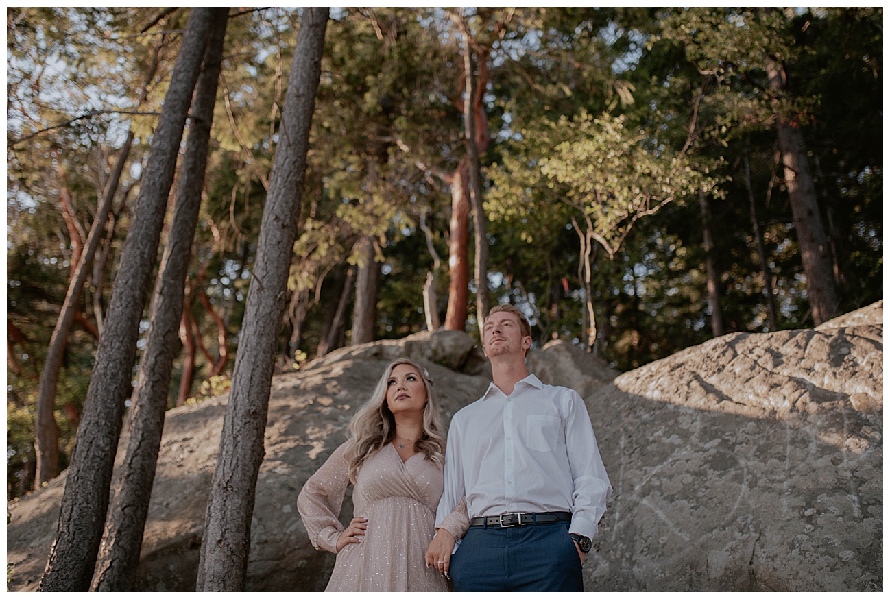 couple looking out with madrone trees behind them in bellingham wa