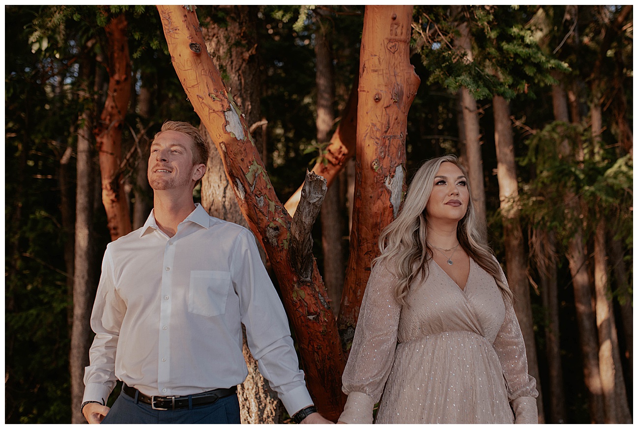 couple standing in front of Madrone tree holding hands looking out to the sea