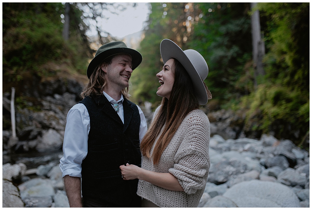 couple in sun hats laughing together in riverbed 