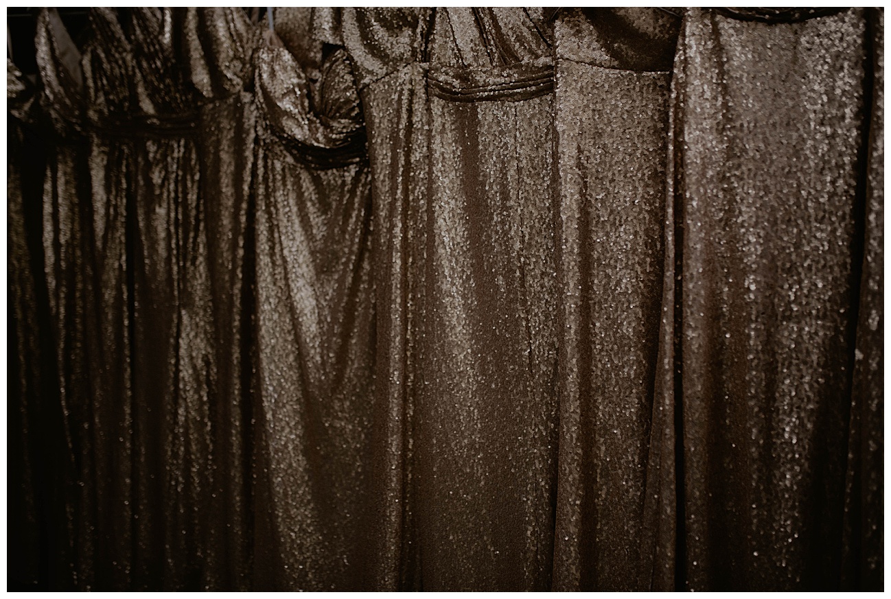 sparkly gold bridesmaids dresses hung up in a line