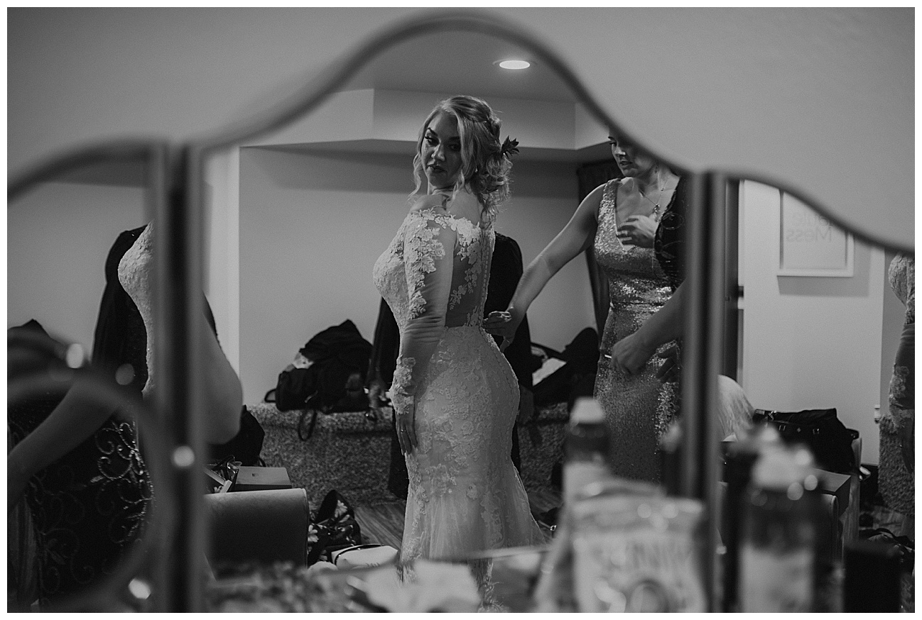 bride getting in her wedding dress with her mom and sister