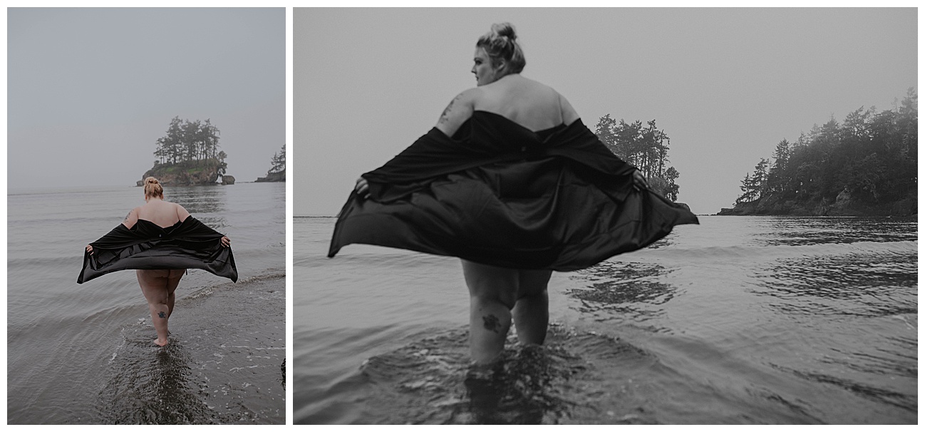 woman walking in water with black robe blowing in the wind on WA coast beach