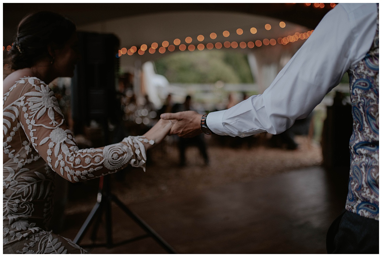 bride and grooms hands holding as they walking to the dance floor