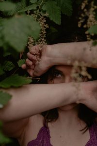 woman covering her face with leaves and her arms in rain