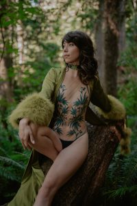 woman in green vintage robe and weed lingerie posing on mossy log